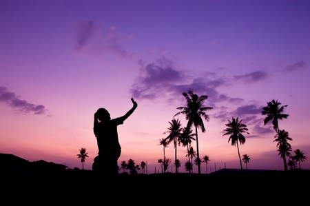 Silhouette of woman taking a picture at coconut fieldの写真素材