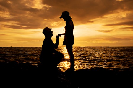 Silhouette of couple on the beach at sunsetの写真素材