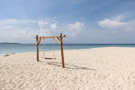 Wooden swing on the sand beach for summer holiday concept.の写真素材