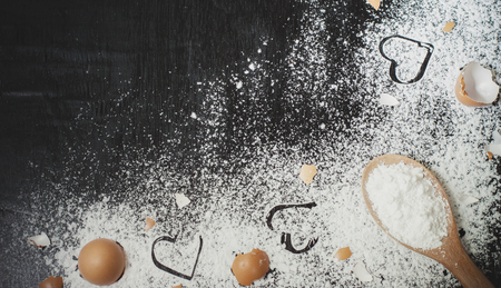 Heart of flour, flour in wooden spoon and eggshell on wooden table for baking backgroundの写真素材