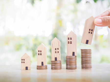 Close up hand holding miniature house on stack of coins for Investment property concept. Saving money for buy a house.の写真素材