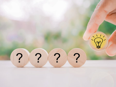 Close up hand arranging wooden block with light bulb and wooden block with question mark for leadership, creative, idea, innovation concept.の写真素材