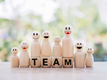 Wooden business figure with happy face standing on wooden block with word the TEAM for teamwork power and confidnce, Successful team leader concept.の写真素材