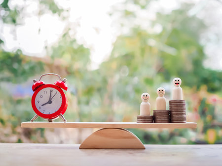 Red alarm and wooden human figure standing on stack of coins for saving concept.の写真素材