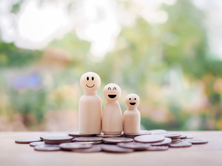 Wooden figure of the family standing on stack of coins for business conceptの写真素材