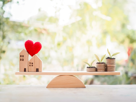 Plants growing up on stack of coins and miniature house on balancing scale for mortgage investment , property conceptの写真素材