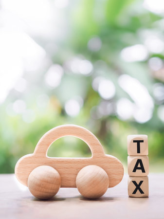Wooden toy car ans Wooden blocks with the word TAX. The concept of paying tax for car.の写真素材
