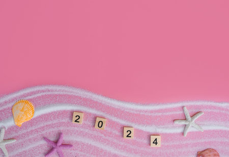 Wooden block with number 2024, seashells, starfish and white sand on pink background. Top view with...