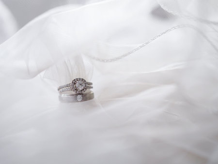 Diamond engagement wedding rings on bridal veil. Wedding accessories, Valentine's day and Wedding day concept.の写真素材