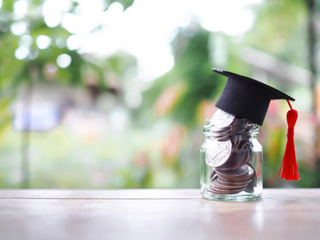 Close up money in the glass bottle with graduation hat. The concept of saving money for education, student loan, scholarship, tuition fees in futureの写真素材