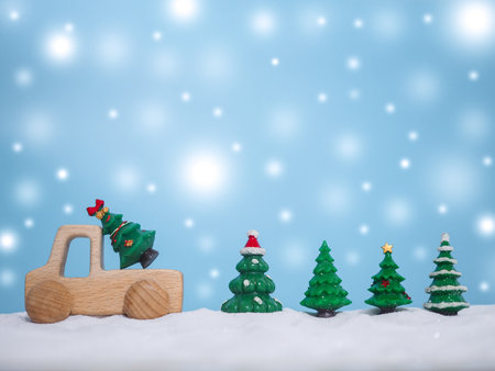 Wooden toy car and Christmas tree with shiny light for Christmas and New Year holidays background, Winter season, falling snow, Copy space for Christmas and New Year holidays greeting card.の写真素材