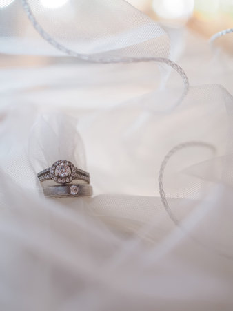 Diamond engagement wedding rings on bridal veil. Wedding accessories, Valentine's day and Wedding day concept.の写真素材