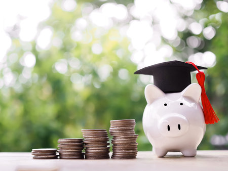 Piggy bank with graduation hat, Glass bottle and stack of coins. The concept of saving money for education, student loan, scholarship, tuition fees in futureの写真素材