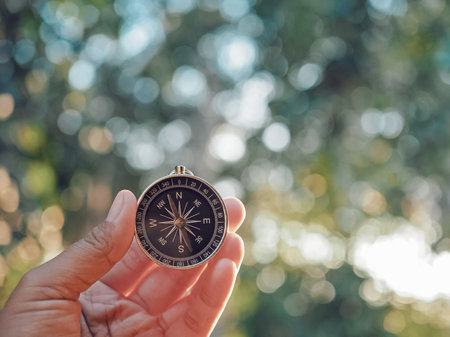 Hand holding compass with nature background. The concept of world tourism day, Searching the right...