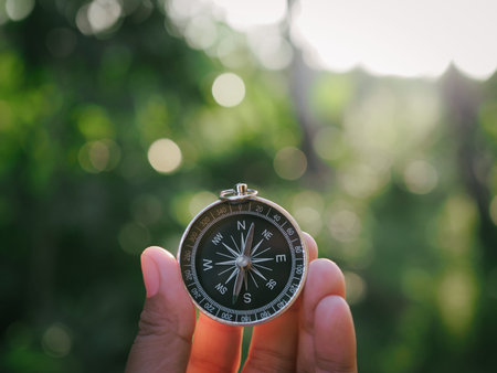 Hand holding compass with nature background. The concept of world tourism day, Searching the right...