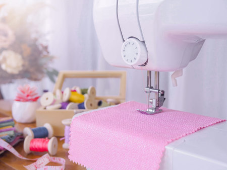 Close up of sewing machine working with pink fabric,  stitch new clothing.