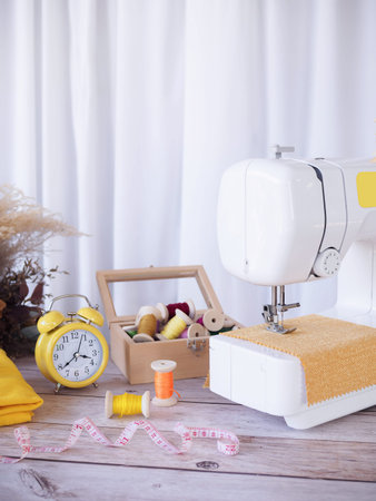 Sewing machine working with yellow fabric, sewing accessories on the table, stitch new clothing.