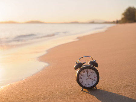 Black alarm clock on the beach in the sunset time. The concept about Time to summer, Travel, Vacation and Relaxationの写真素材