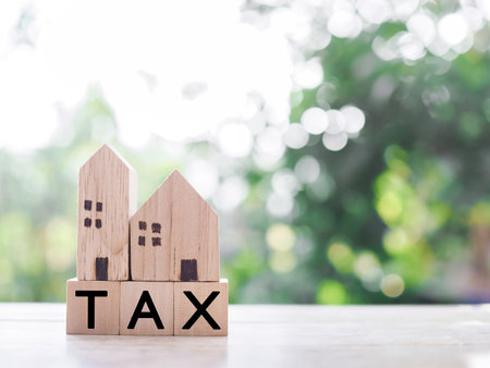 Miniature house and Wooden blocks with the word TAX. The concept of payment tax for house, Property investment, House mortgage, Real estateの写真素材