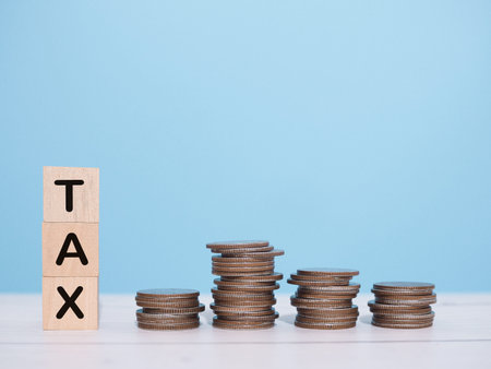 Wooden blocks with the word TAX and stack of coins. The concept about saving money and manage time to paying taxの写真素材