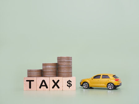 Toy car, wooden blocks with the word TAX and stack of coins. The concept of saving and manage money to success transportation, Paying tax and car loanの写真素材