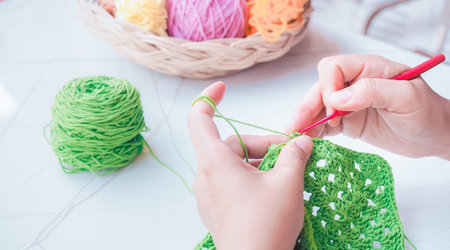 Close-up of woman hand knitting with green wool