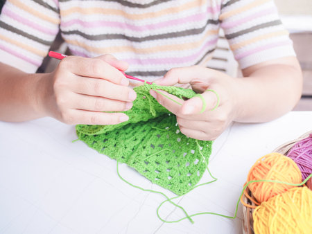 Close-up of woman hand knitting with green woolの写真素材