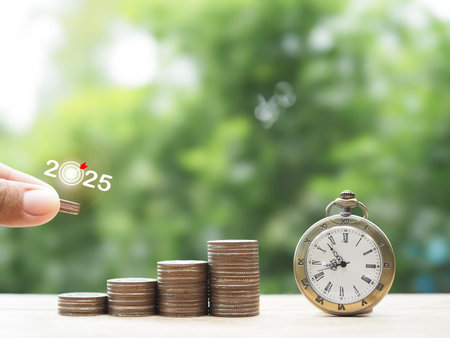 Close up hand putting coin into stack of coins and Vintage watch. The concept of saving money and...