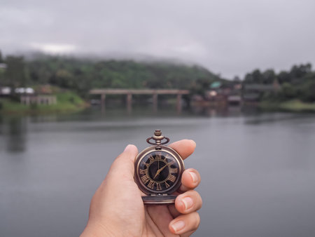 Close up of vintage pocket watch in woman hand with river as background.