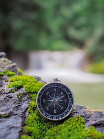 Compass on the rock with waterfall as background. The concept of world tourism day, Searching the...