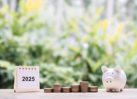2025 desk calendar, Piggy bank and stack of coins. The concept of saving money, business growth,...