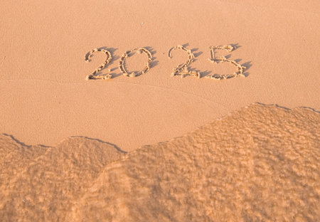 2025 year handwritten on the beach in the sunset time. New Year 2025 concept