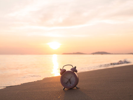 Alarm clock on the beach in the sunset time. The concept about Time to summer, Travel, Vacation and...