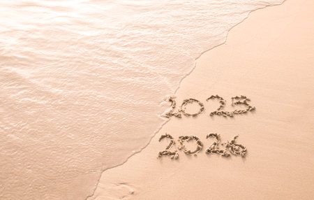 Handwritten inscription 2025 and 2026 on the beach in the sunset time. The concept of Goodbye 2025 and Happy New Year 2026の写真素材