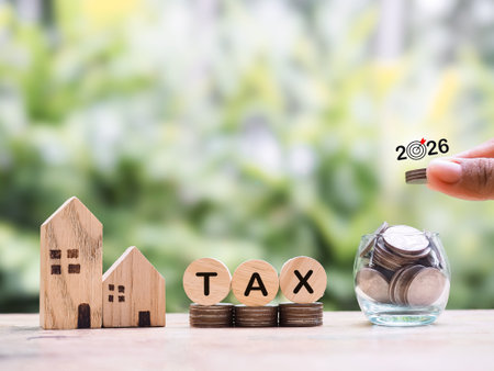 Miniature house, Wooden blocks with the word TAX and stack of coins. The concept of payment tax for house, Property investment, House mortgage, Real estate in year 2026の写真素材