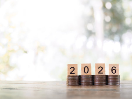 Wooden blocks with the number 2026 on stack of coins. The concept of saving money, Financial, Investment and Business growing in year 2026.の写真素材