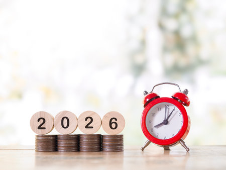 Red alarm clock, Wooden blocks with the number 2026 on stack of coins. The concept of saving money for manage time to success business in year 2026の写真素材
