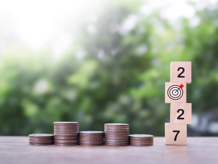 Wooden blocks with the number 2027 and stack of coins. The concept of saving money, Financial, Investment and Business growing in year 2027.の写真素材