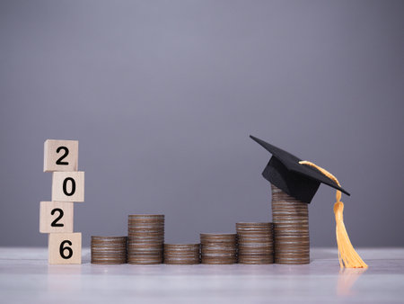 Wooden blocks with the number 2026 and stack of coins with graduation hat. The concept of saving money for education, student loan, scholarship, tuition fees in year 2026の写真素材