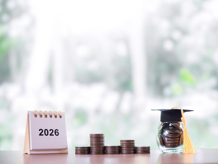 Study goals. 2026 desk calendar, Glass bottle with graduation hat and stack of coins. The concept of...