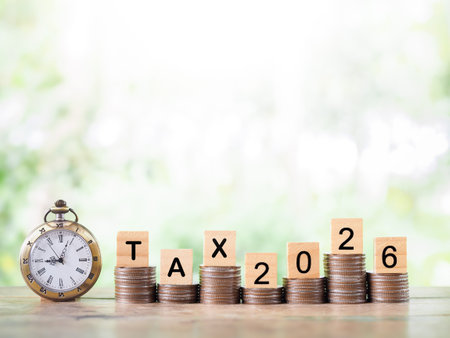 Vintage watch,  Wooden blocks with the word TAX, Nunber 2025 and stack of coins. The concept about...