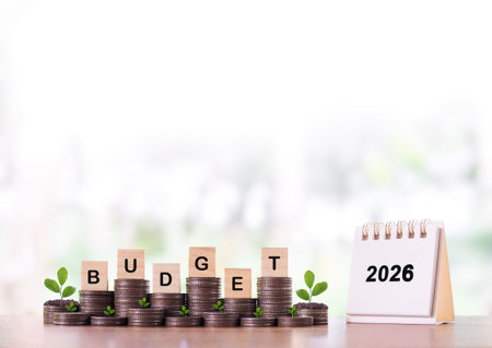 2026 desk calendar, Wooden blocks with the word BUDGET and plants growing up on stack of coins. The concept about budget planning and allocation in year 2026の写真素材