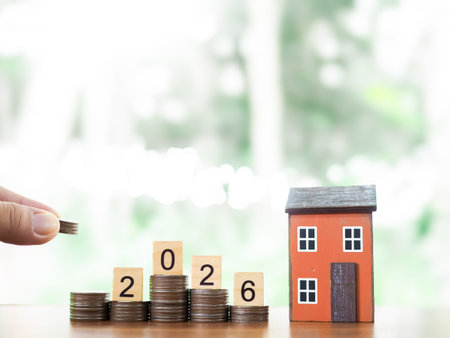 Miniature house, Wooden blocks with number 2026 on stack of coins. The concept of saving money for...