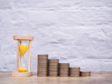 Hourglass and stack of coins. The concept of saving money for manage time to success business.