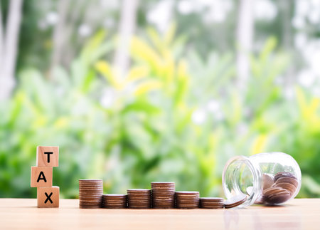 Wooden blocks with the word TAX and stack of coins. The concept of prepare to pay tax in the futureの写真素材
