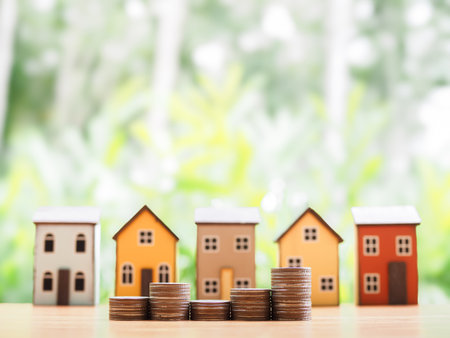 Stack of coins with Miniature house background. The concept of saving money for house, Property investment, House mortgage, Real estate in the future.の写真素材