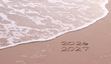 Handwritten inscription 2026 and 2027 on the beach in the sunset time. The concept of Goodbye 2026 and Happy New Year 2027の写真素材