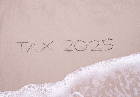 TAX 2025 handwritten with ocean waves on a sandy beach.の写真素材