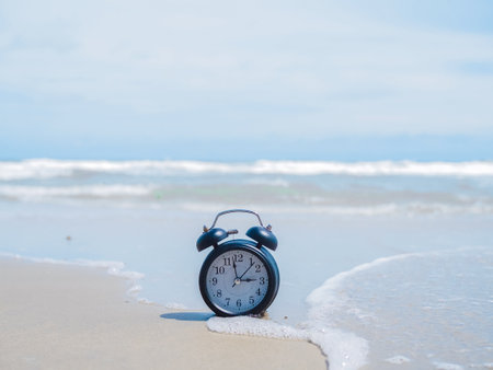 Black alarm clock on the beach with ocean waves. The concept about Time to summer, Travel, Vacation and Relaxationの写真素材