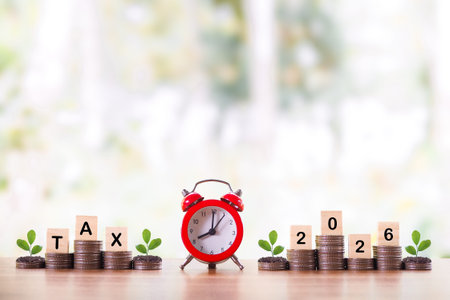 Red alarm clock and plants growing up on stack of coins. The concept about saving money and manage...